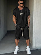 Man wearing a black outfit with white Men's Casual T-Shirt and Shorts Setsneakers in an urban setting